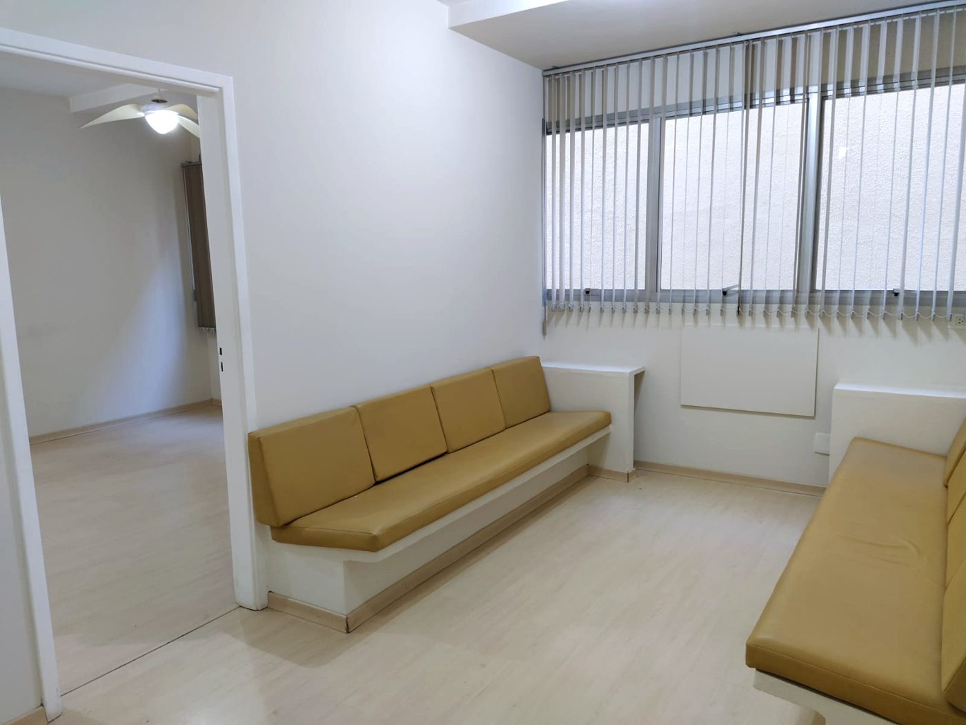 Recepção com bancos estofados embutidos e porta para o consultório